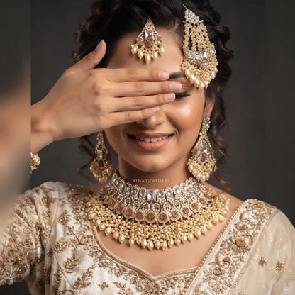Pearl ivory bridal choker necklace set with tikka, jhoomar and earrings on a bride in ivory outfit