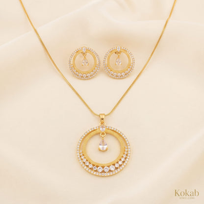 Close up of gold-plated concentric rings jewelry set featuring clear crystal stones and a suspended teardrop zircon center