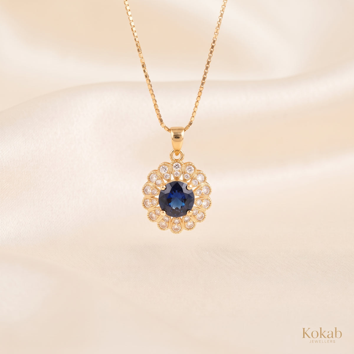 Close-up of gold plated royal blue floral halo pendant necklace with sparkling zirconia stones