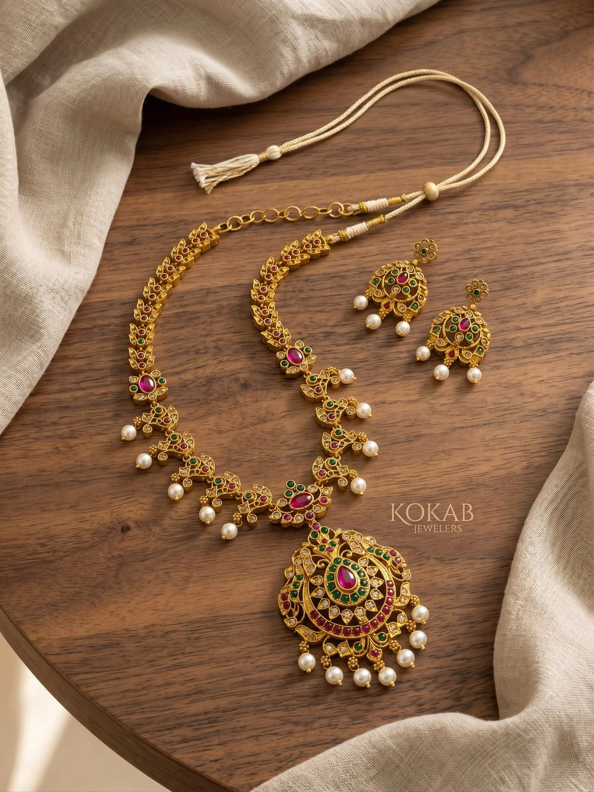 Gold plated mango design long necklace with ruby emerald stones on wood