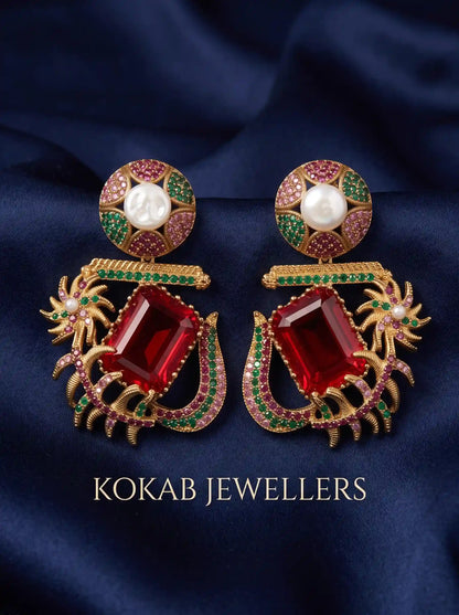 Kashmiri statement earrings with ruby red emerald-cut stone, pearl stud and antique gold design on navy satin