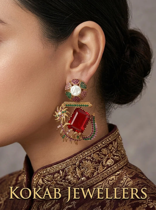 Woman wearing Kashmiri ruby red stone and pearl statement earrings with a gold embroidered outfit