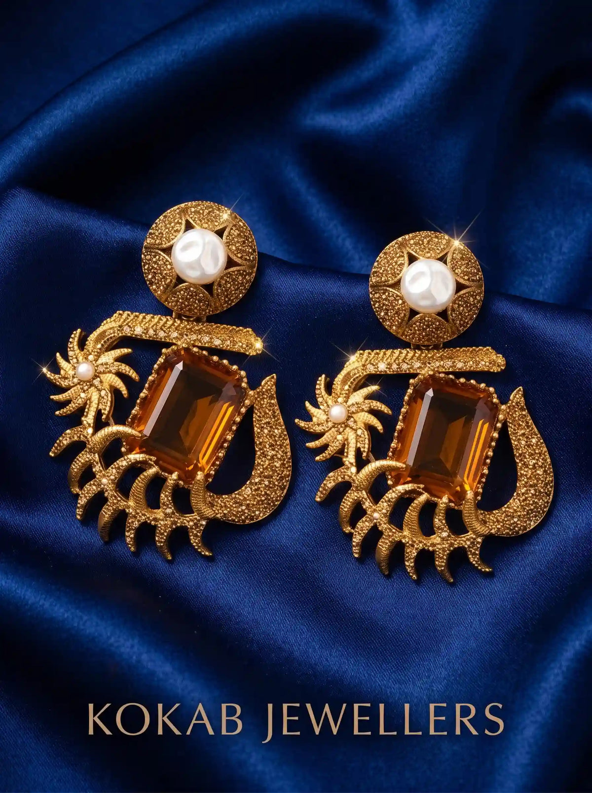 Antique gold Kashmiri earrings with amber emerald-cut stone and pearl stud on blue satin