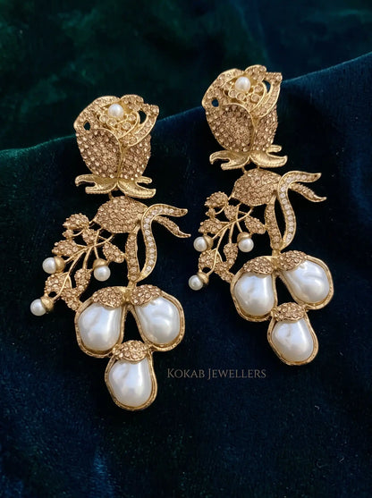 Champagne gold stone rose earrings with three baroque pearl drops on dark green velvet
