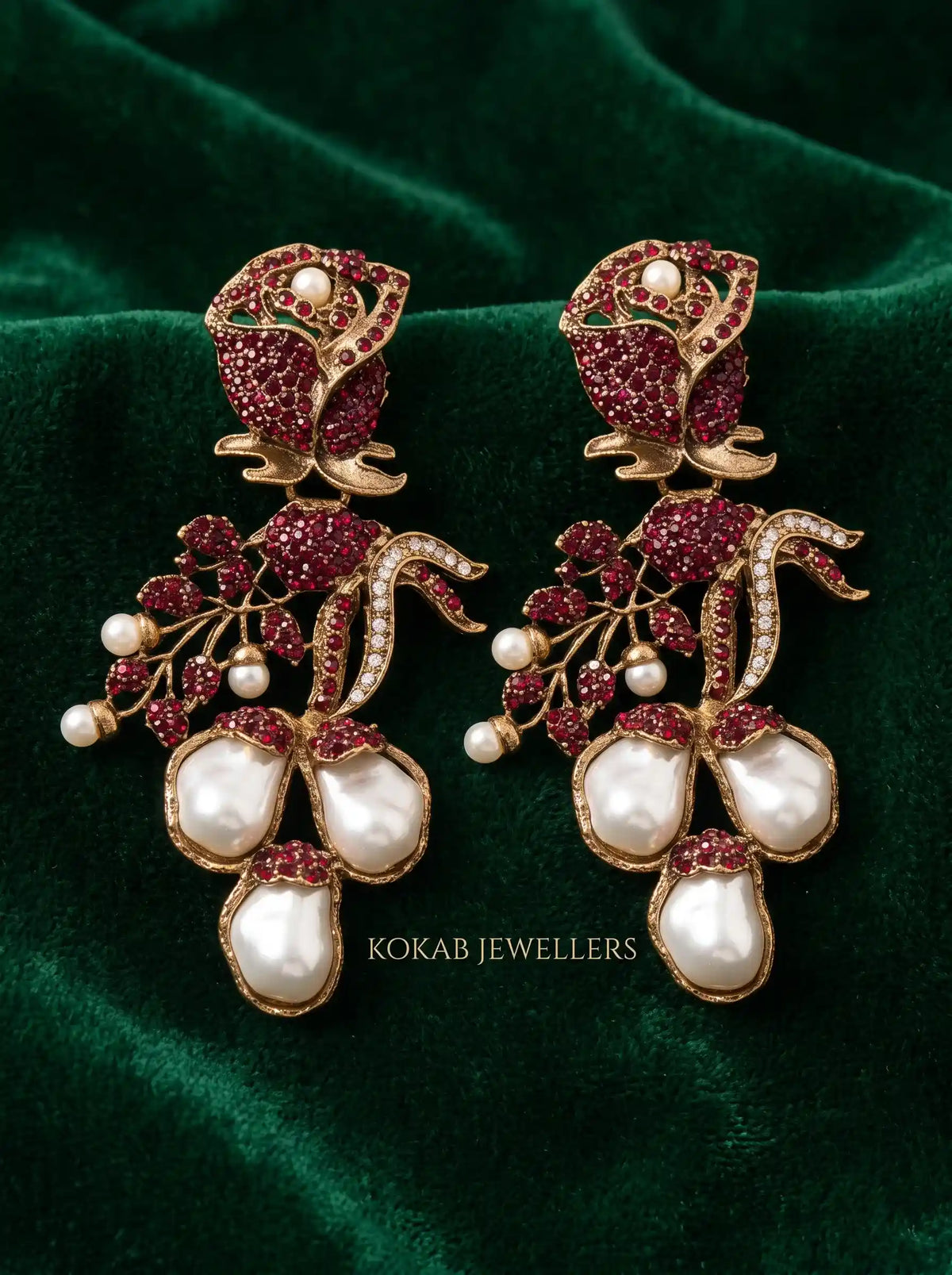 Ruby red rose bud Kashmiri earrings with three baroque pearl drops on green velvet